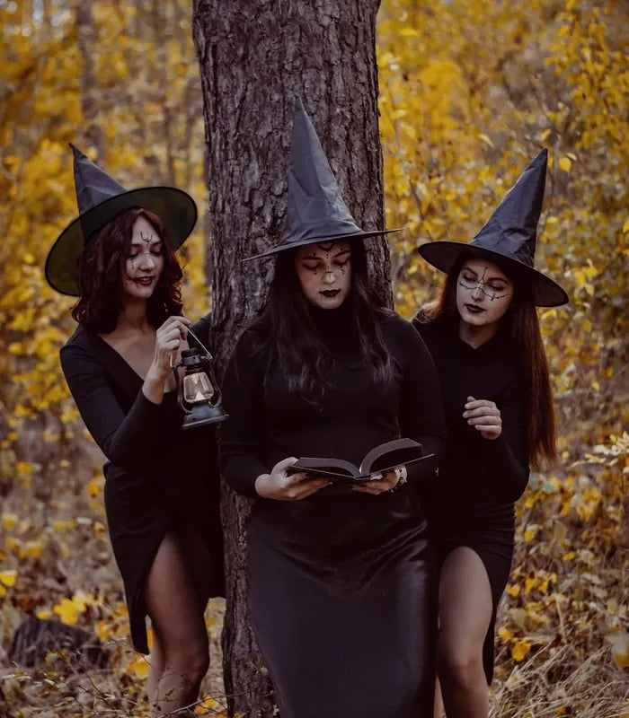 Three friends dressed as witches in an autumn forest